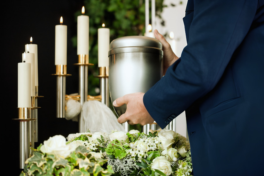 Funeral Director holding a passed loved one in a nickel brushed urn.