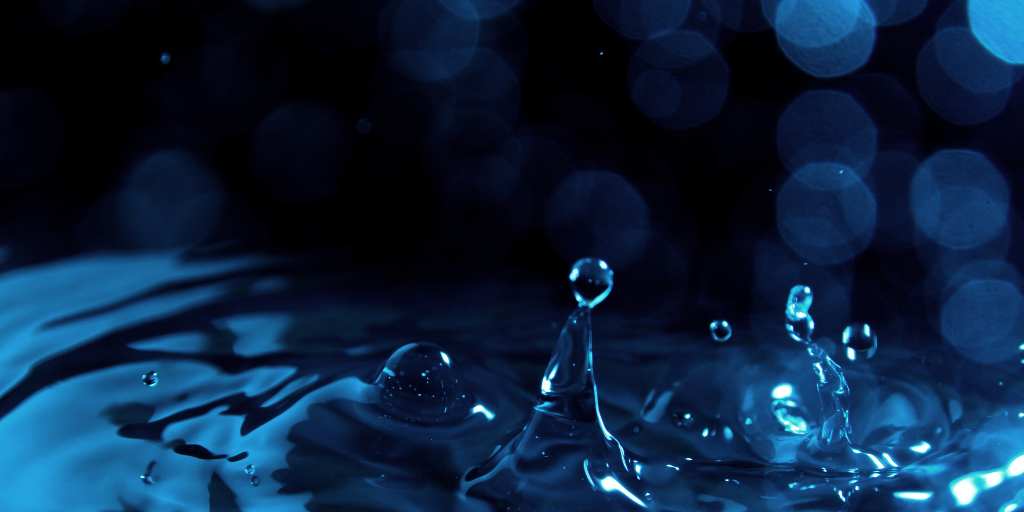 Micro view of a water droplet splashing onto a water surface.