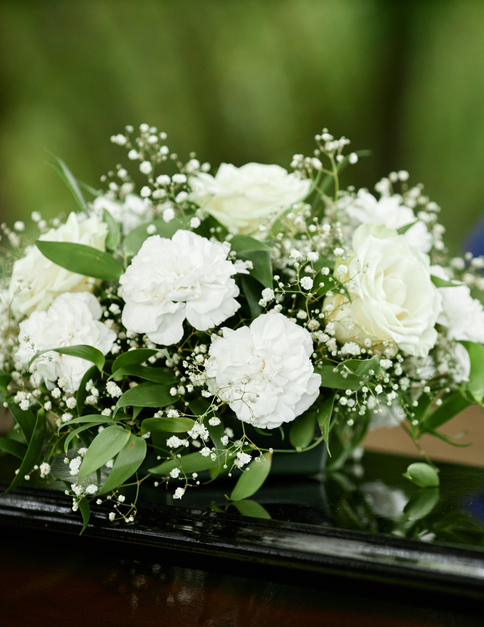 A bouquet of white flowers rests on top of a coffin.