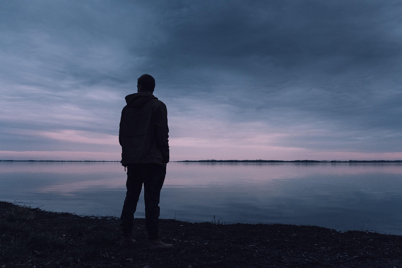 a man standing alone on the shore of a lake
