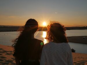 Two women sitting together at sunset