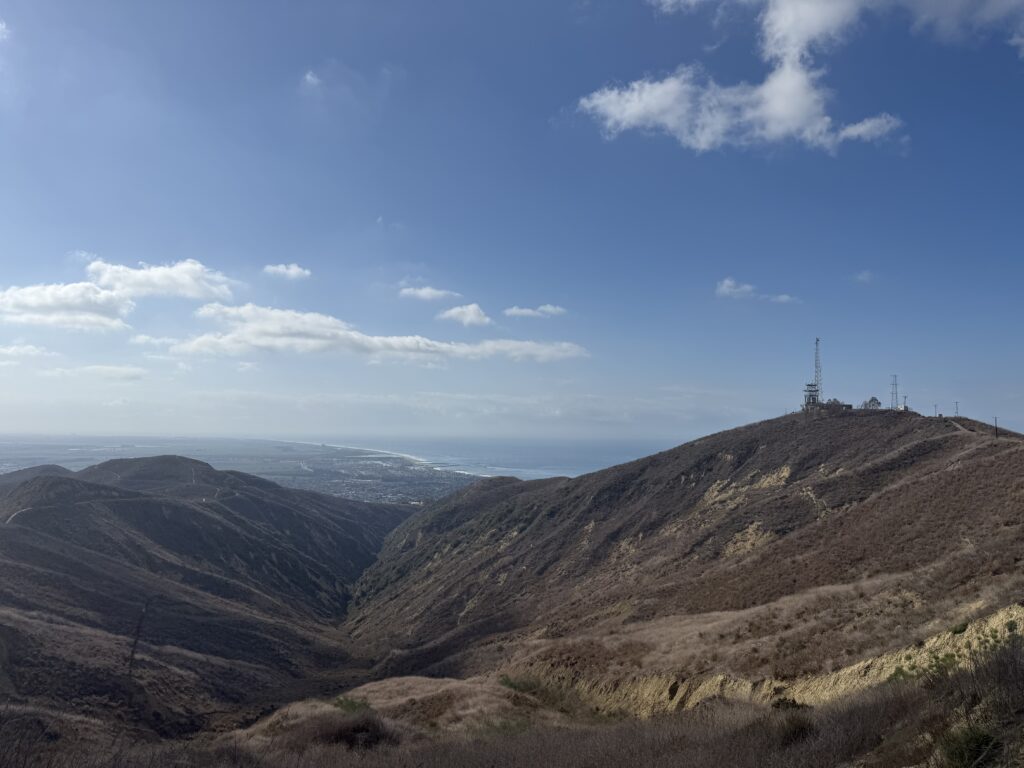 Dry hills forming a valley with distant coastline visible.