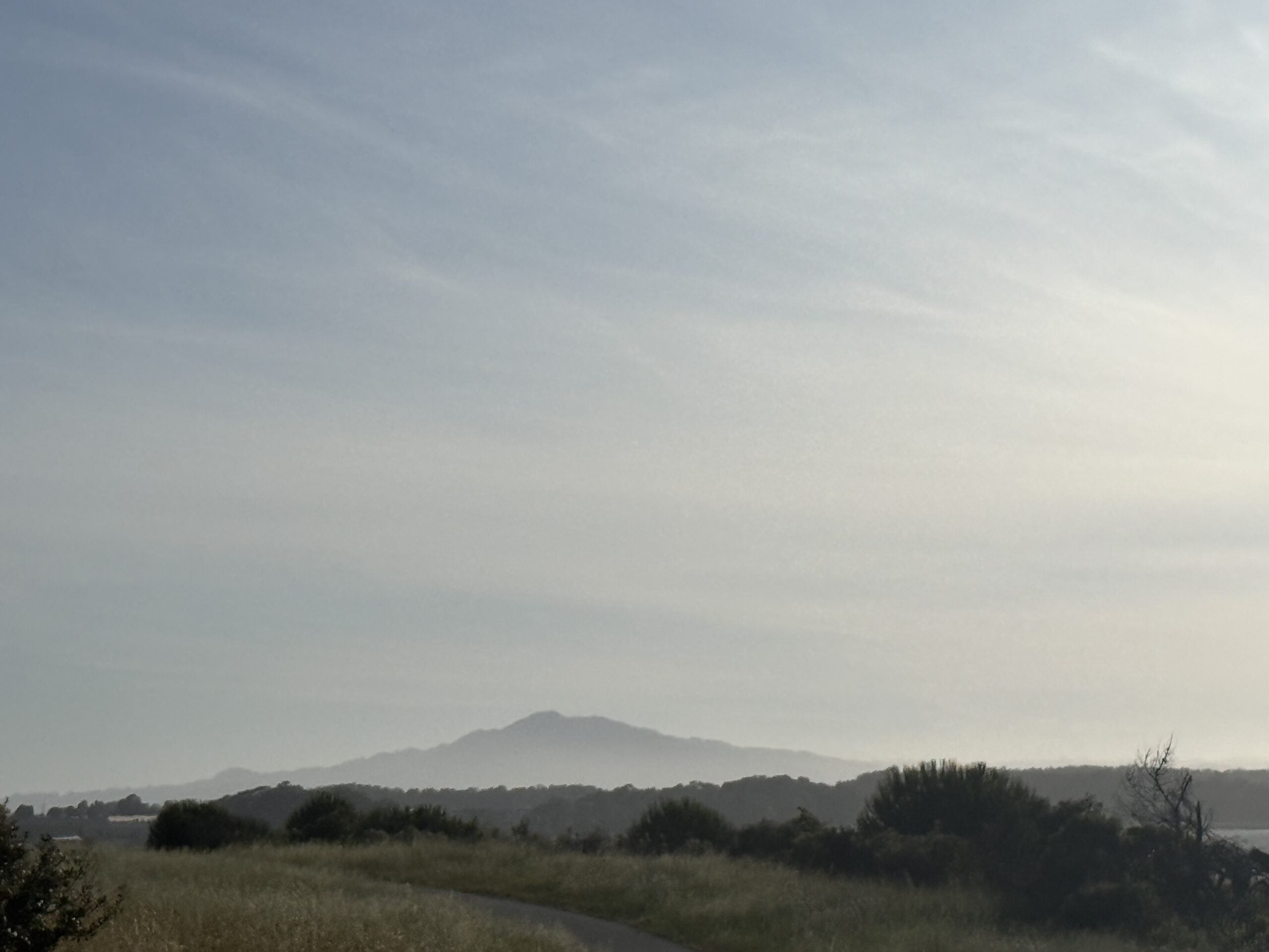A hazy sky stretches over distant hills and a quiet landscape