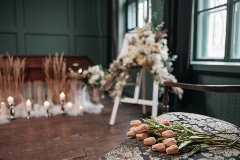 A quiet memorial setting with soft candlelight, floral arrangements, and tulips resting on a table.