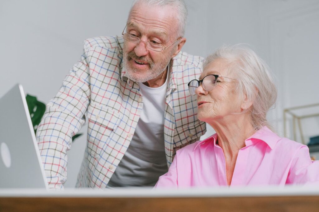 An older couple looking at a laptop together and sharing a warm conversation.