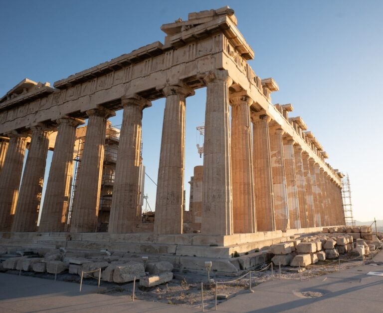The Parthenon in Athens, with ancient stone columns illuminated by warm sunlight.